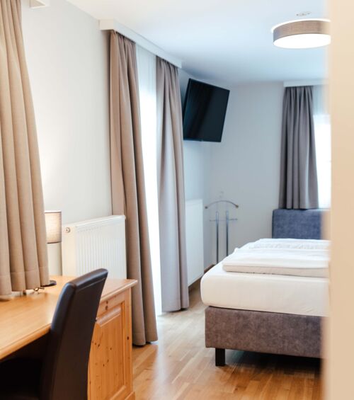 Ein Flat screen TV, ein Schreibtisch und ein Doppelbett im Doppelzimmer.