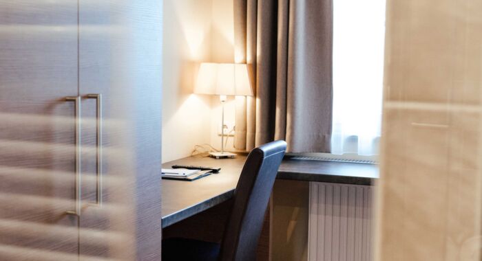 Ein Schreibtisch mit Leselampe im hellen Einzelzimmer des 4-Sterne hotels Kirchbichl