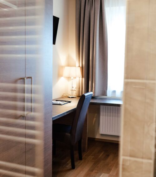 Ein Schreibtisch mit Leselampe im hellen Einzelzimmer des 4-Sterne hotels Kirchbichl
