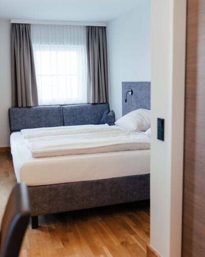 Ein Doppel Bett und eine Couch im Doppelzimmer des Landgasthofs Kirchbichl