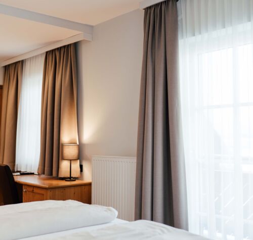 Ein Doppel Bett mit blick zu den Balkontüren des Doppelzimmers im Landgasthof Kirchbichl
