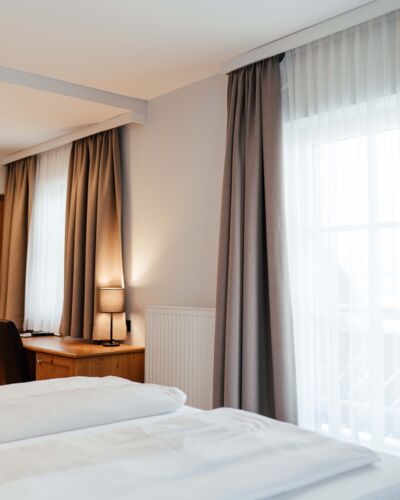 Ein Doppel Bett mit blick zu den Balkontüren des Doppelzimmers im Landgasthof Kirchbichl