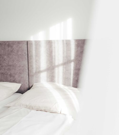 Sonne scheint auf das Doppelbett in Doppelzimmer des Gästehauses des Landgasthofs Kirchbichl.