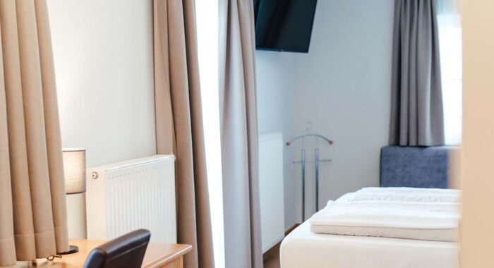 Ein Flat screen TV, ein Schreibtisch und ein Doppelbett im Doppelzimmer.