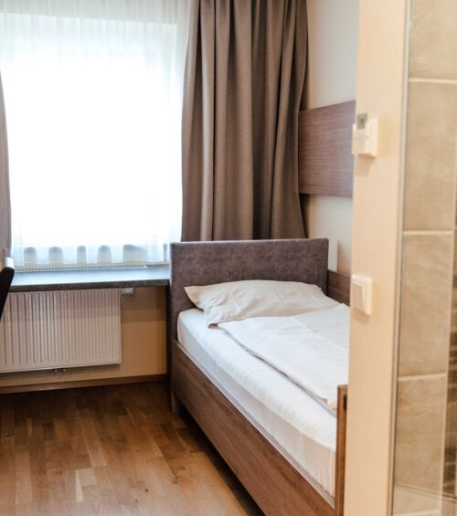 Einzelbett im Einzelzimmer mit großem Fenster im Hotel Kirchbichl