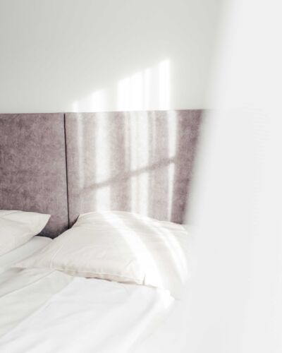 Sonne scheint auf das Doppelbett in Doppelzimmer des Gästehauses des Landgasthofs Kirchbichl.