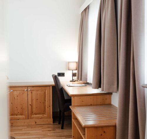 Das Doppelbettzimmer im Gästhaus mit einem Schreibtisch vor dem Fenster im Landgasthof Kirchbichl