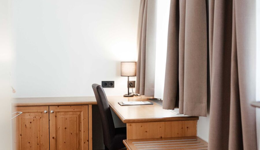Das Doppelbettzimmer im Gästhaus mit einem Schreibtisch vor dem Fenster im Landgasthof Kirchbichl