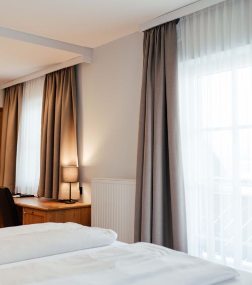 Ein Doppel Bett mit blick zu den Balkontüren des Doppelzimmers im Landgasthof Kirchbichl