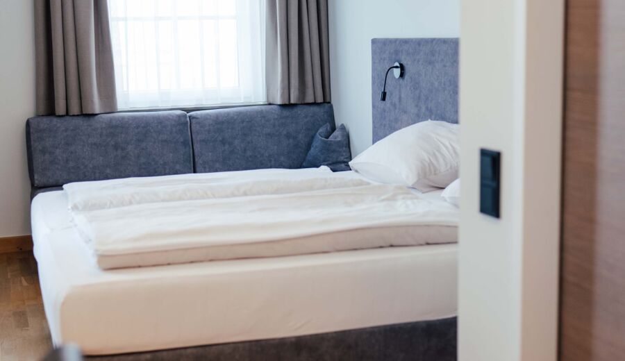Ein Doppel Bett und eine Couch im Doppelzimmer des Landgasthofs Kirchbichl