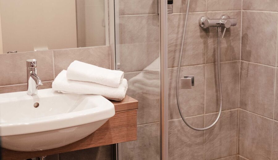 Eine Walk-In Dusche und ein Waschbecken im Badezimmer des Twinzimmers im 4-Sterne Hotel Kirchbichl