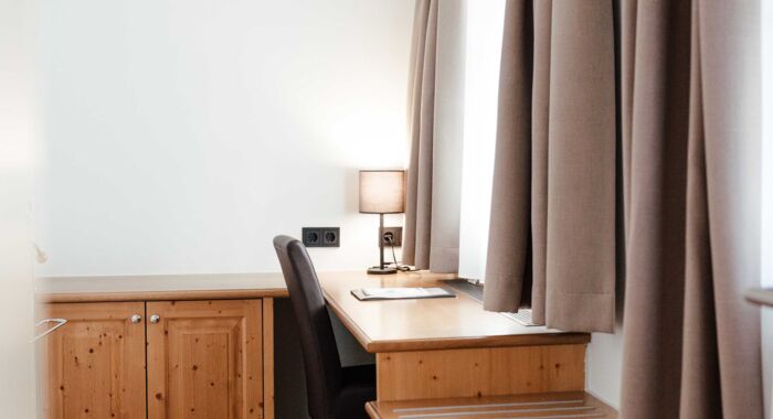 Das Doppelbettzimmer im Gästhaus mit einem Schreibtisch vor dem Fenster im Landgasthof Kirchbichl