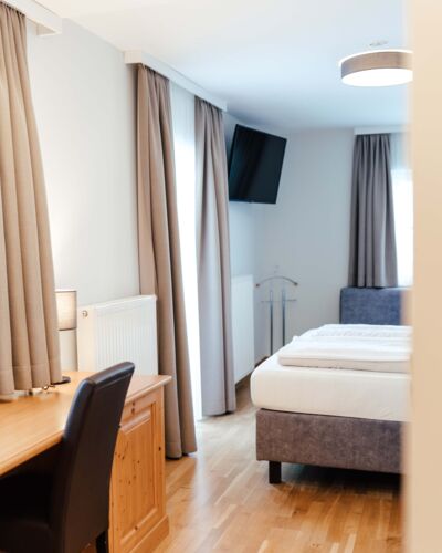Ein Flat screen TV, ein Schreibtisch und ein Doppelbett im Doppelzimmer.