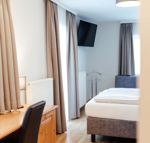 Ein Flat screen TV, ein Schreibtisch und ein Doppelbett im Doppelzimmer.