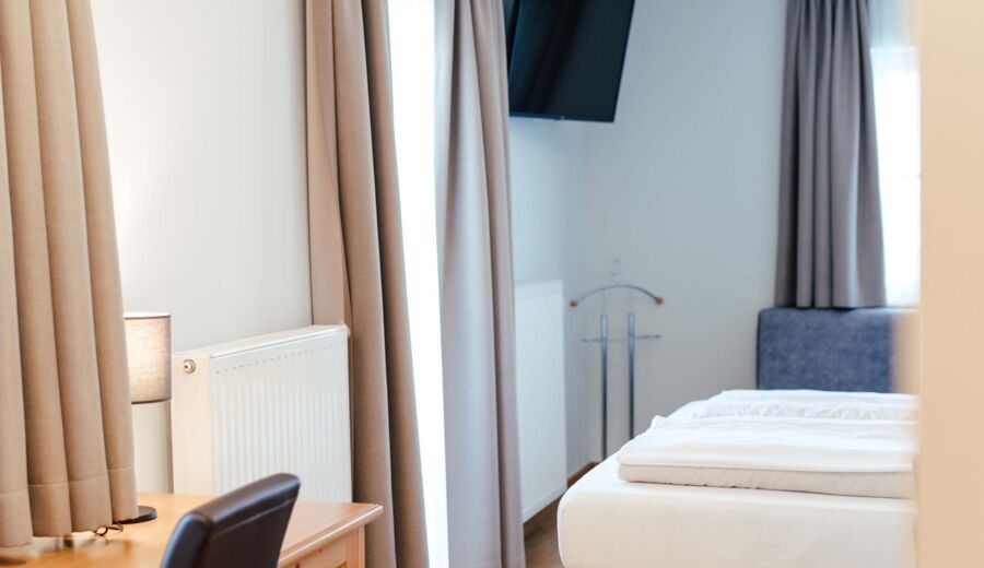 Ein Flat screen TV, ein Schreibtisch und ein Doppelbett im Doppelzimmer.