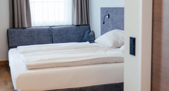 Ein Doppel Bett und eine Couch im Doppelzimmer des Landgasthofs Kirchbichl