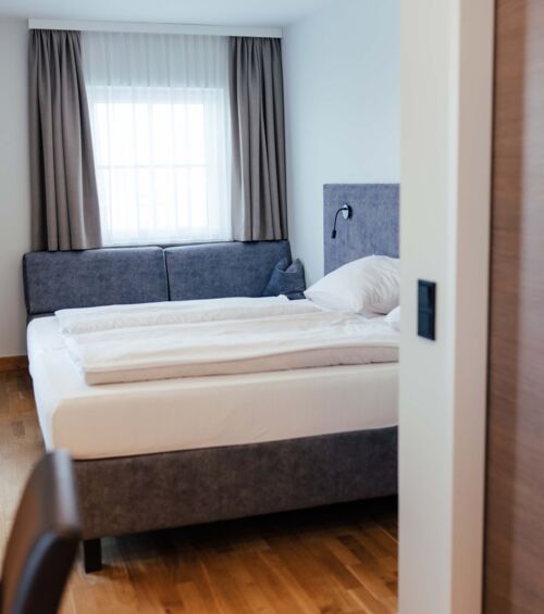 Ein Doppel Bett und eine Couch im Doppelzimmer des Landgasthofs Kirchbichl