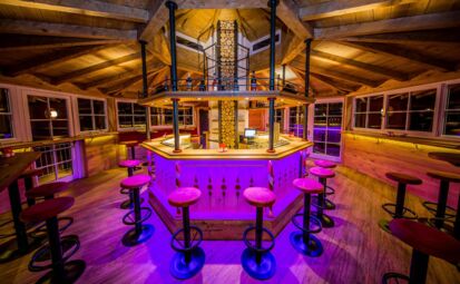 Die Rundbar aus Holz mit roten Barhocker im Salettl in Hallwang