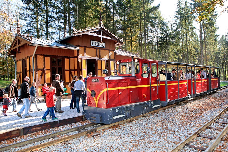 Visitors board the museum train in the forest at Salzburg's open-air Freilichtmuseum