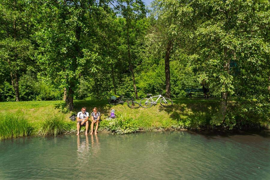 Two people sit beside a lake and enjoy a break from their cycling tour of the Salzburg region