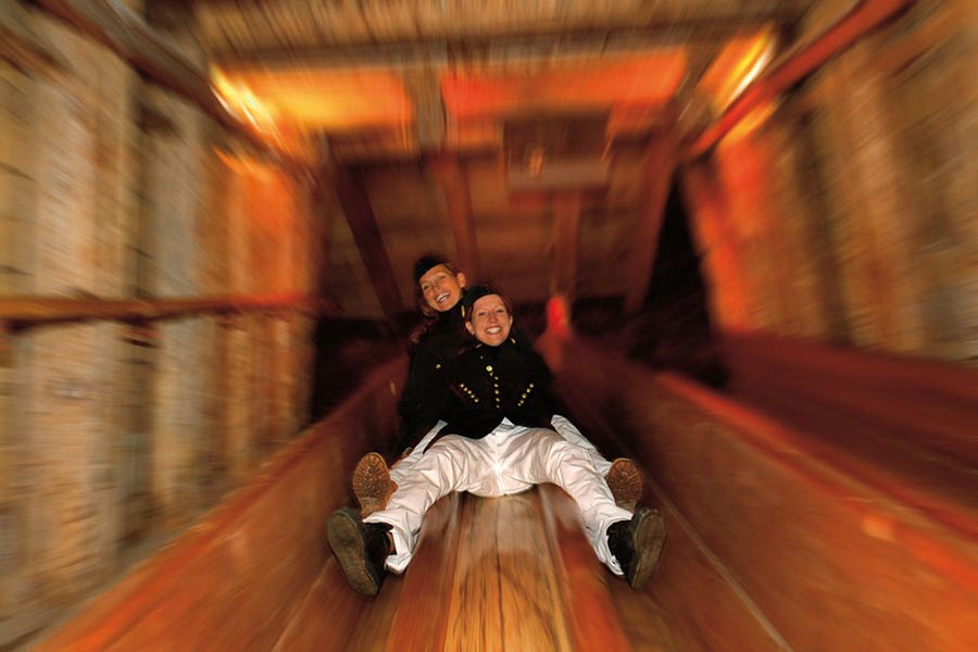 Two women descend the slide in the salt mines